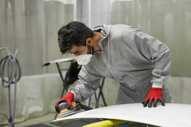 Solunum cihazında beyaz tenli genç bir araba temizleyicisi ve makineli koruyucu gözlükler.