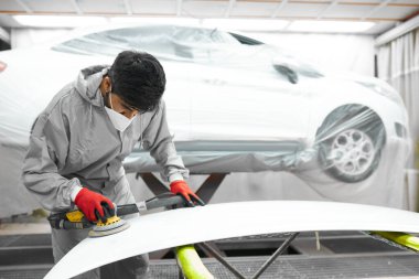 Araba, oto yıkama. Yörünge parlatıcısı olan genç bir tamirci.