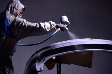 Kendine güvenen tamirci serviste araba boyuyor.