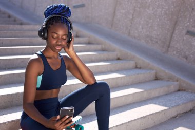 Güzel, sportif kadın müzik dinler ve akıllı telefon kullanır.