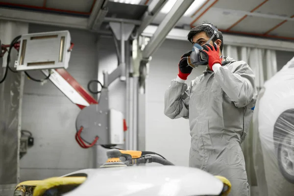 Ernstige auto monteur dragen beschermende masker voor het schilderen of polijsten van auto — Stockfoto