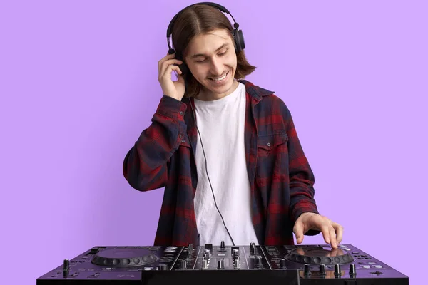 Positiver männlicher DJ spielt Musik auf violettem Hintergrund — Stockfoto
