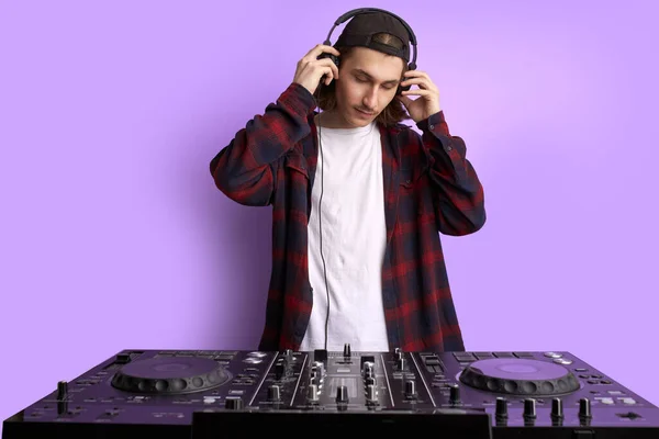 Dj man i vita hörlurar bakom dj konsol, gör sång med dj controller. — Stockfoto