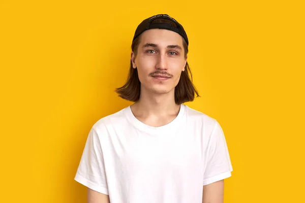 Joven hombre hipster complacido con el pelo largo aislado sobre fondo amarillo — Foto de Stock