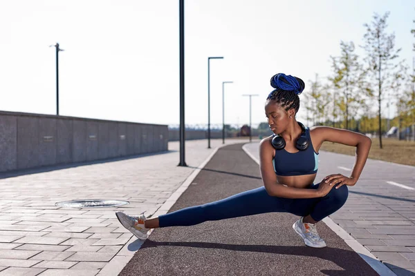 アスリートアフロ女性屋外ランニング中にハムストリングレッグの筋肉を伸ばす — ストック写真