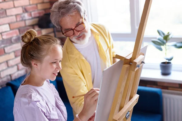 Büyük büyükbaba küçük kıza resim yapmayı öğretiyor. — Stok fotoğraf