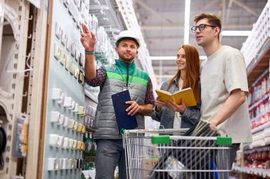 Üniformalı işçiler müşterilere danışıyor, gerekli bilgileri veriyor