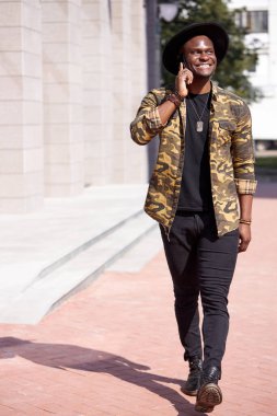 Modern yakışıklı adam yürürken telefonda konuşuyor.