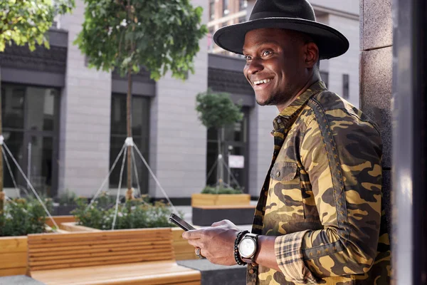 Hombre africano satisfecho usando el teléfono inteligente en la calle —  Fotos de Stock