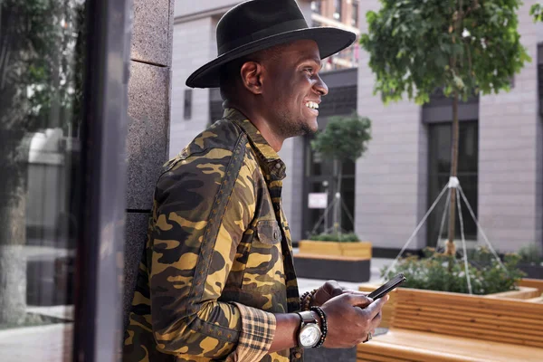 Hombre africano satisfecho usando el teléfono inteligente en la calle — Foto de Stock