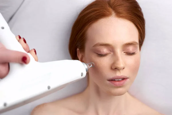 cosmetologist doing photo rejuvenation procedure for woman patient