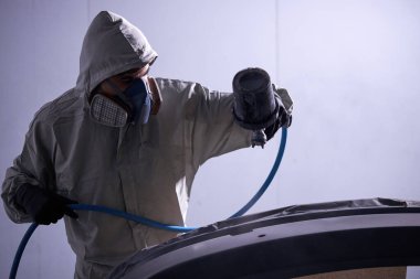 Kendine güvenen tamirci arabada cila sıkıyor.