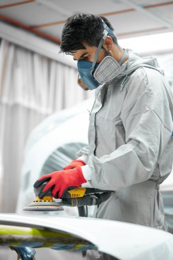 Genç oto tamircisi arabayı cilalıyor ve parlatıyor.