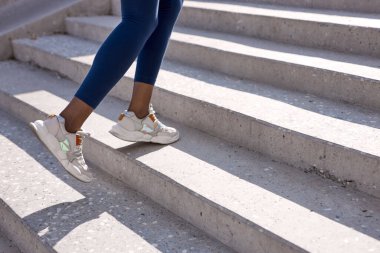 Afrikalı kız merdivenlerde antrenman yapıyor, inip çıkıyor.