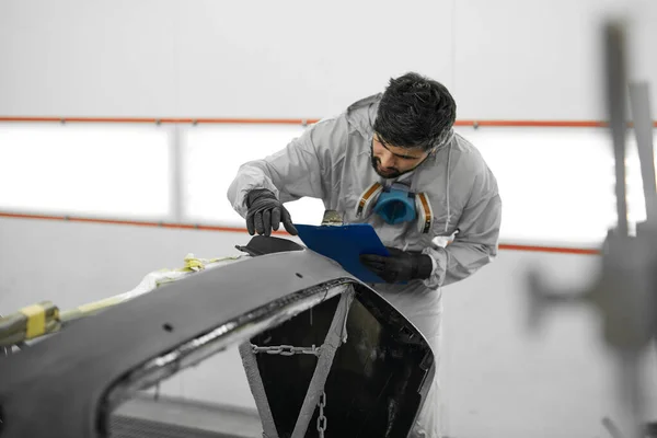 Joven mecánico de automóviles macho realiza diagnósticos de la carrocería del coche antes de su renovación — Foto de Stock