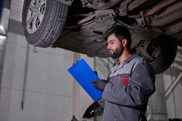 Kaukaski auto mechanik pisanie pracy listy kontrolnej do schowka — Zdjęcie stockowe