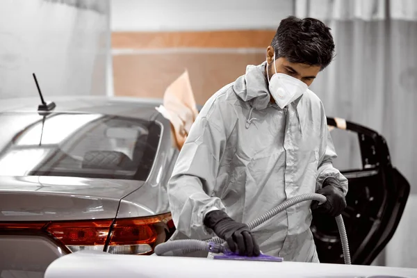 Jonge Kaukasische auto schoner in ademhalingsapparaat en beschermende bril polijsten auto met machine — Stockfoto