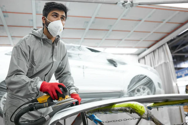 Jonge Kaukasische auto schoner in ademhalingsapparaat en beschermende bril polijsten auto met machine — Stockfoto