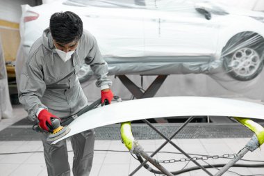 Solunum cihazında beyaz tenli genç bir araba temizleyicisi ve makineli koruyucu gözlükler.