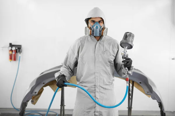 Portrait of man in protective uniform going to painting body of car in the service — Stock Photo, Image