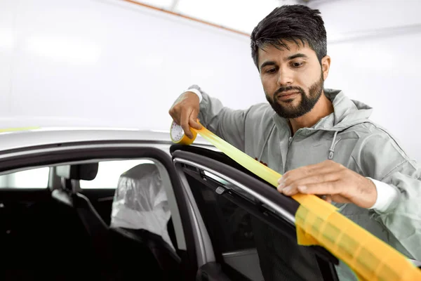 Mechanik muž se žlutou papírovou páskou omítky auto pro leštění — Stock fotografie