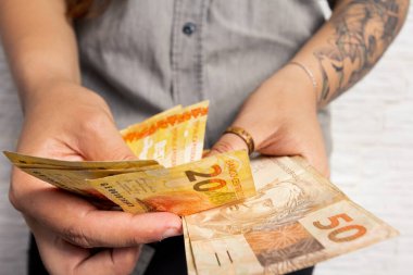 Alternatif kadın elinde büyük miktarda para tutuyor, Brezilya 'dan bir sürü para. İş, gelir, kredi, ödeme, satın alma, zenginlik kavramı.