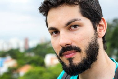 Kendine güveni olan bir erkeğe yaklaş. Bulanık arkaplan, ağaçlar ve binalar, kentsel.