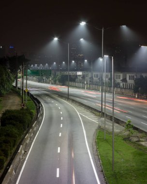 Metropolis 'te gece, parlak ışıklar ve araçlar yolda. Nehrin yanındaki Sao Paulo şehir otoyolu. Skyline, arabalar ve trafik yüksek hızda ilerliyor..
