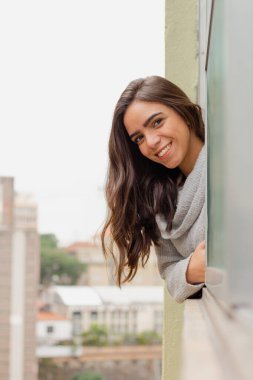 Sao Paulo şehrinde pencereden dışarı bakan genç bir kadın. Gelecek hakkında düşünceler, duygular, planlama ve sükunet. Şehir sahnesindeki binalar.
