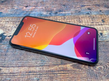 BALI, INDONESIA JUNE 29 Haziran 2020: Iphone X ahşap desenli, üst görüşlü bir masada kullanılmıştır. en son iPhone ürünleri.