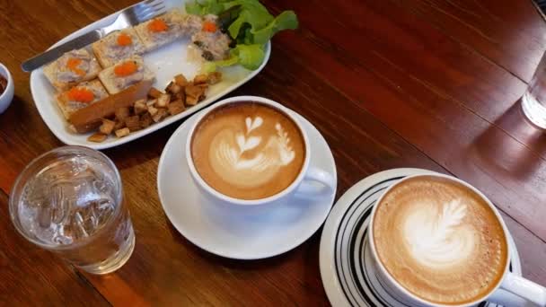 午前中に木製のテーブルにコーヒーのカプチーノのカップ — ストック動画