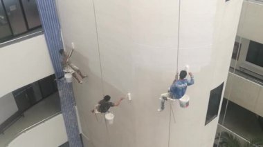 Bangkok, Tayland - Aralık, 3 2018: Ressamlar büyük ip ile yüksek binalar üzerinde boya vardır.