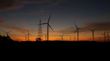  Rüzgar türbinleri ve gün batımına karşı güç hatları. Khao Kho District, Phetchabun Eyaleti, Tayland temiz enerji sistemi.