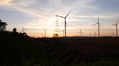  Rüzgar türbinleri ve gün batımına karşı güç hatları. Khao Kho District, Phetchabun Eyaleti, Tayland temiz enerji sistemi.