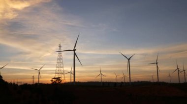  Rüzgar türbinleri ve gün batımına karşı güç hatları. Khao Kho District, Phetchabun Eyaleti, Tayland temiz enerji sistemi.