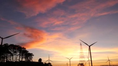  Rüzgar türbinleri ve gün batımına karşı güç hatları. Khao Kho District, Phetchabun Eyaleti, Tayland temiz enerji sistemi.