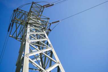 Mavi gökyüzü arka planında yüksek voltaj direği.