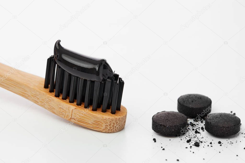 Black toothpaste on toothbrush with activated charcoal pills 