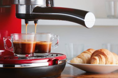 Two cups of espresso on espresso machine with croissants on plate  clipart