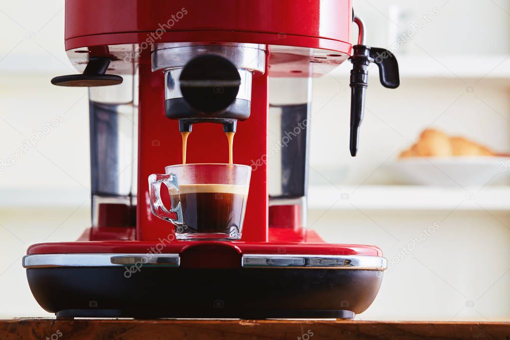 Making fresh coffee going out from a coffee espresso machine in glass transparent coffee cup 