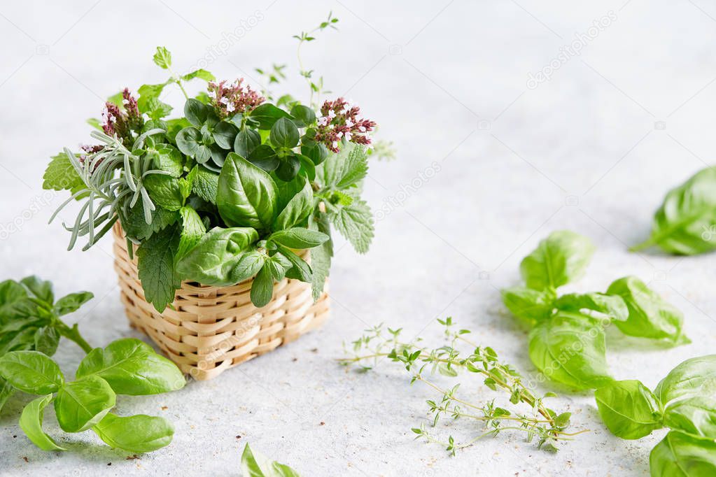 Assorted herbs in small wicker basket on grey surface