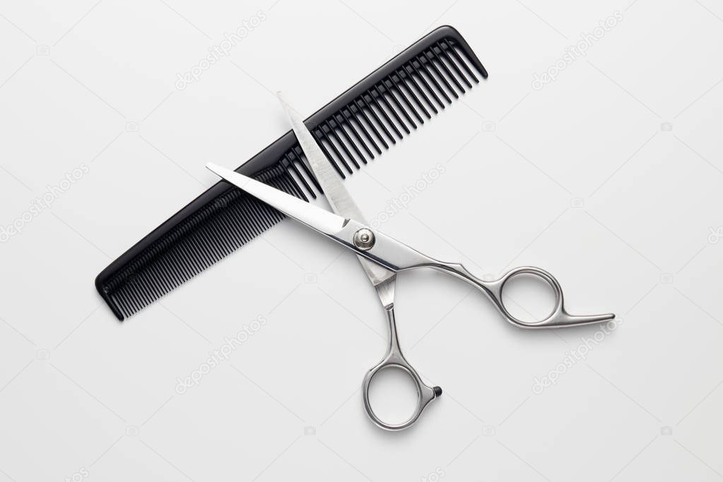 Hairdressers scissors and comb on white background