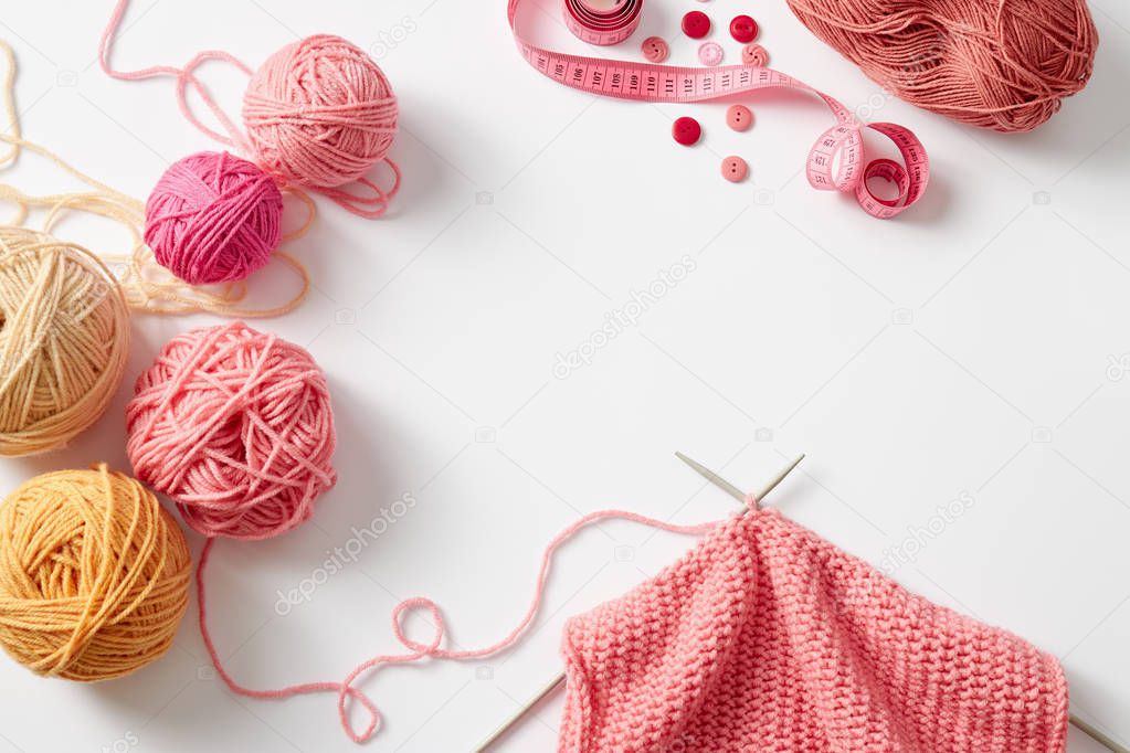 piece of knitting with balls of yarn and knitting needles