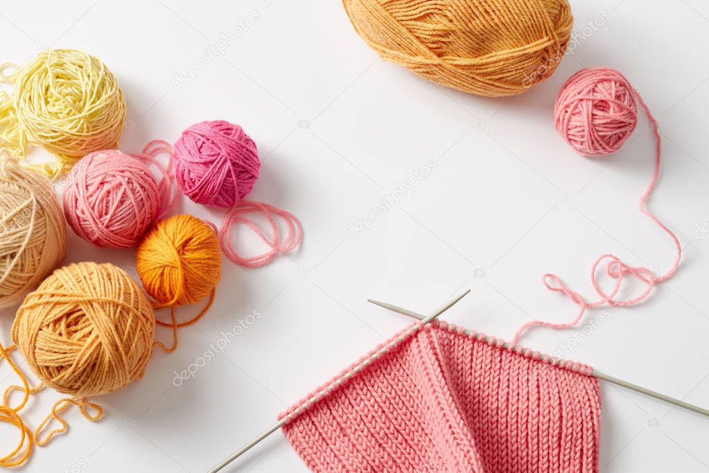 piece of knitting with balls of yarn and knitting needles
