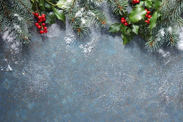 圣诞节背景与冷杉树和冬青浆果在蓝色石头背景覆盖在雪与拷贝空间 — 图库照片