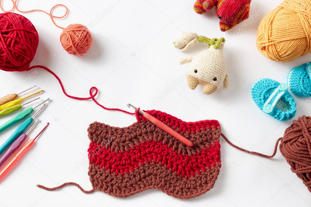 Colorful crochet project with hook and yarn, on white background.