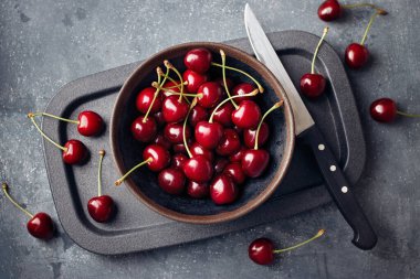 Küçük bir kasede kirazlar ve masanın etrafına saçılmış..