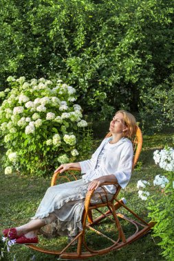 Orta yaşlı kadın bahçede hasır sandalye dinlenme