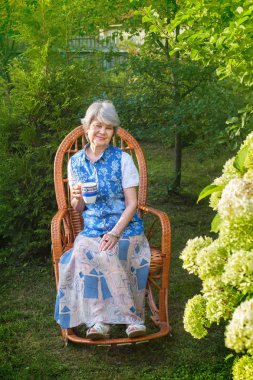 Hasır sandalye ülke evinde istirahat çay ile üst düzey kadın