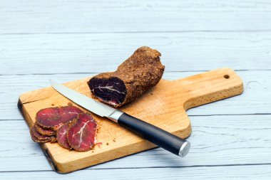 Ahşap tahta üzerinde kürlenmiş sığır pastırması dilimleri.